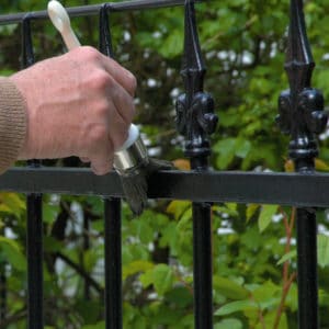 Black Owatrol Deco being applied to metal gate with a brush
