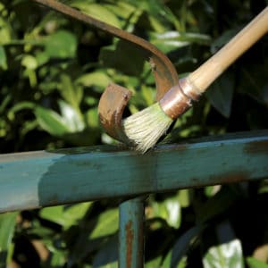 Owatrol Oil being applied to a rusted metal gate with a brush