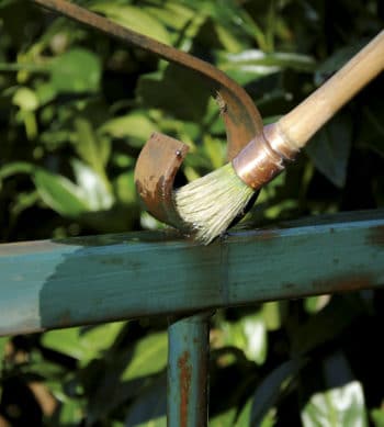 Owatrol Oil being applied to a rusted metal gate with a brush