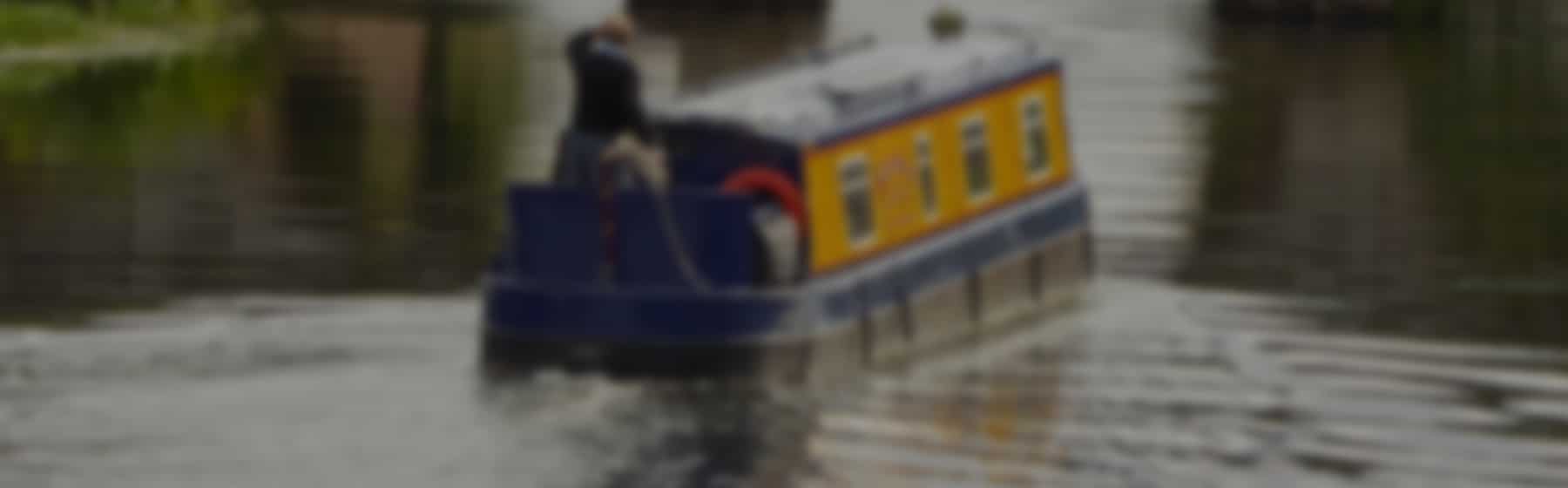 Man cruising on a blue narrowboat