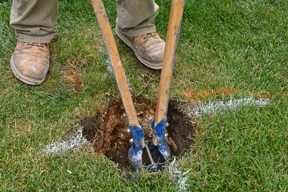 Man using a fence post digging tool