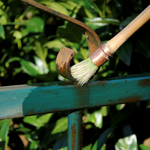 Owatrol oil being applied to a rusted metal fence