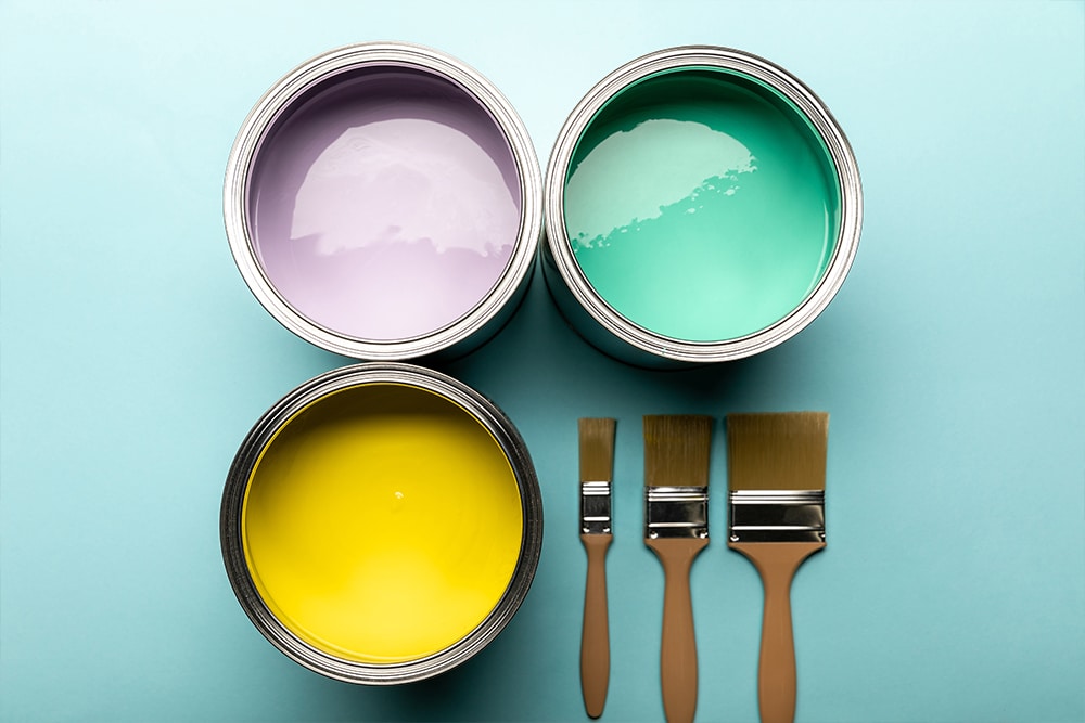 Different coloured pots of paint and brushes