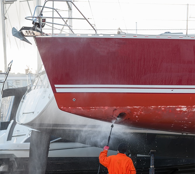 Man cleaning a boat with a pressure washer
