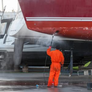 Man cleaning a boat with a pressure washer