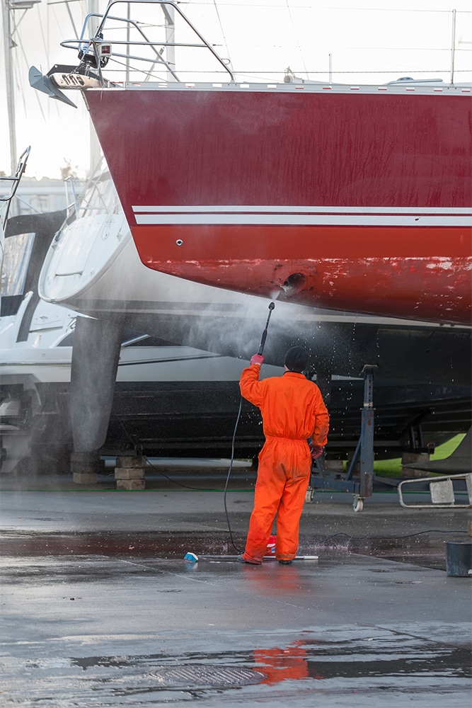 Man cleaning a boat with a pressure washer