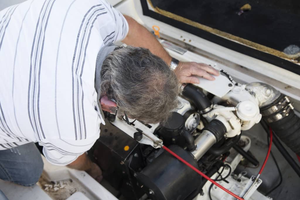 man looking at boat engine