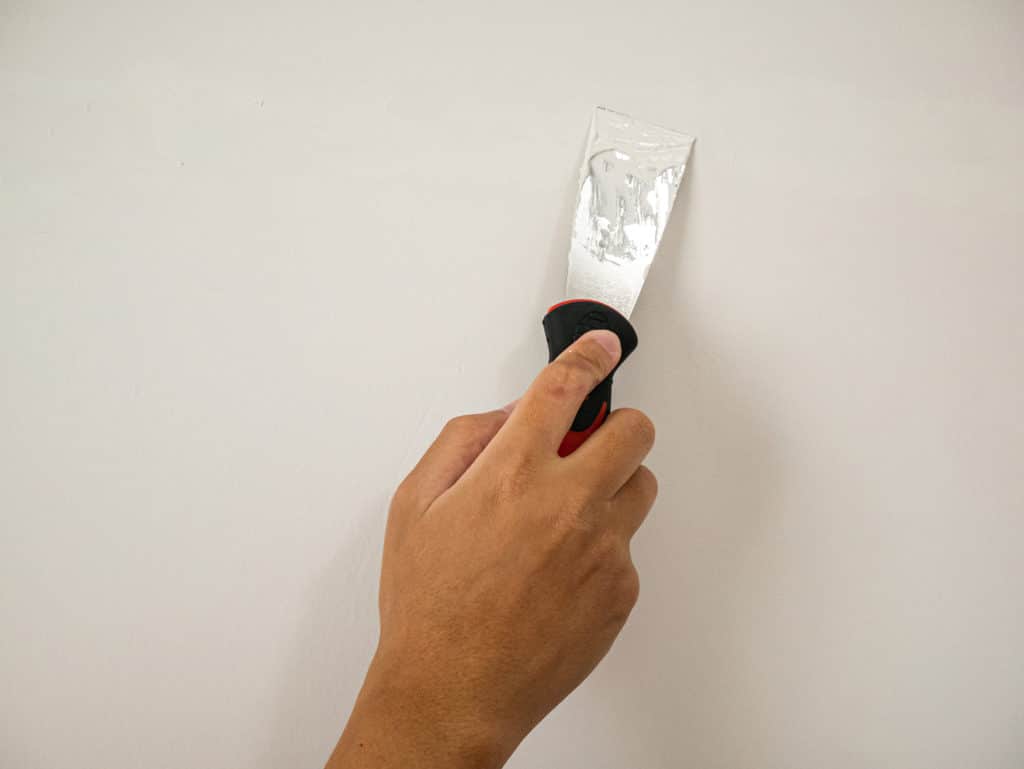 Hand with filler and filling knife on interior wall