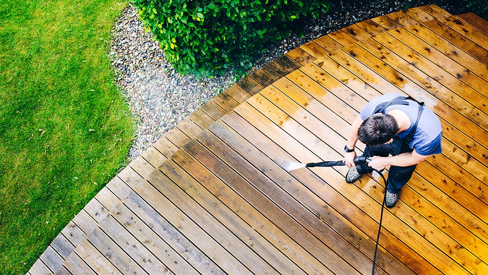 Aerial view of a man using a pressure washer on a garden deck