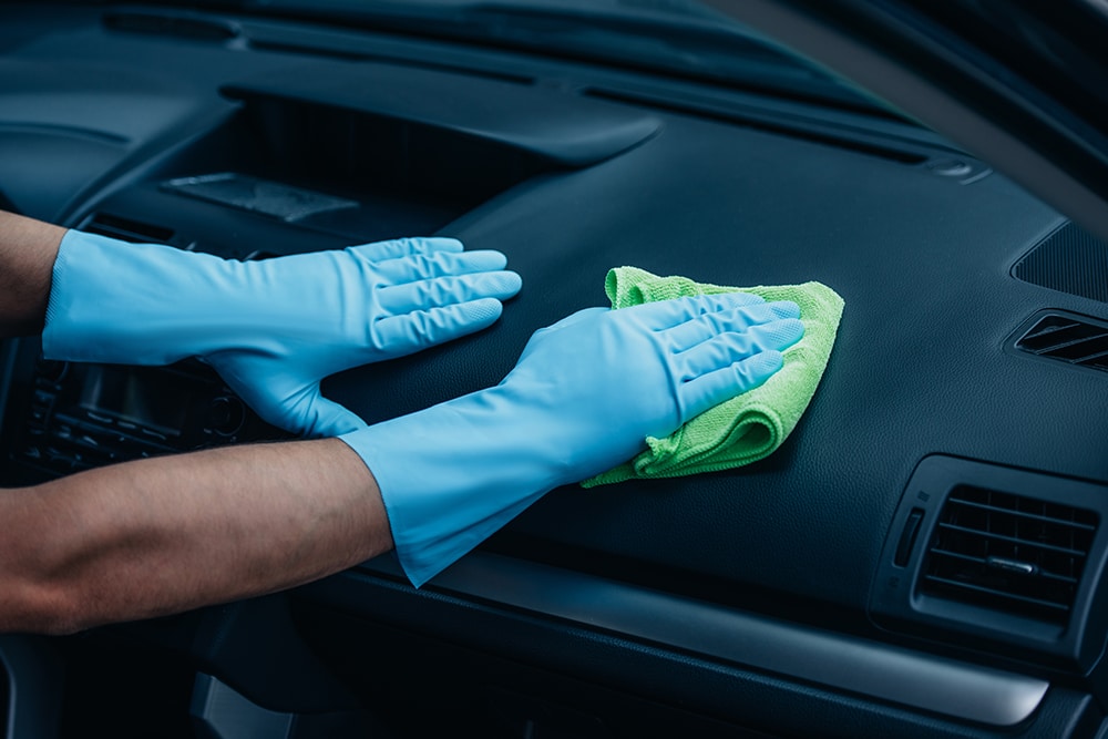 Person wiping down car dashboard